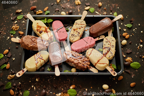 Image of Set of delicious white and milk chocolate and strawberry ice cream on a stick served in metal tray