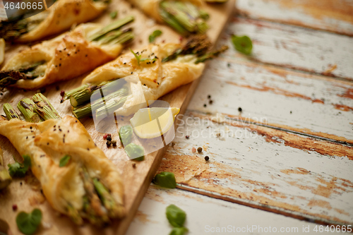 Image of Baked green asparagus wrapped in puff pastry. Served on wooden board. With copy space