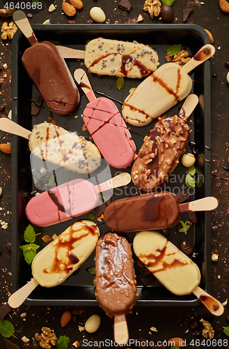 Image of Assortment of various popsicle ice cream, white and dark chocolate, with almonds, rusty background