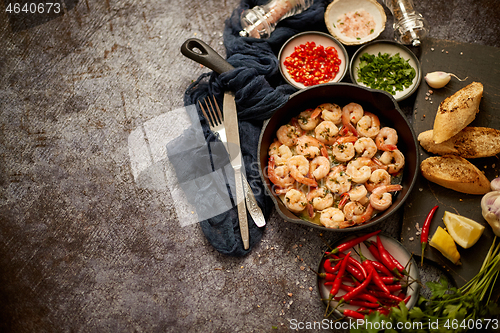 Image of Grilled shrimps in cast iron grilling pan with fresh lemon, parsley, chili, garlic white wine sauce
