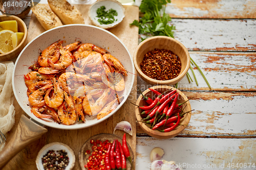 Image of Top view of prawns shrimps roasted on pan with herbs placed on rustic wooden kitchen table