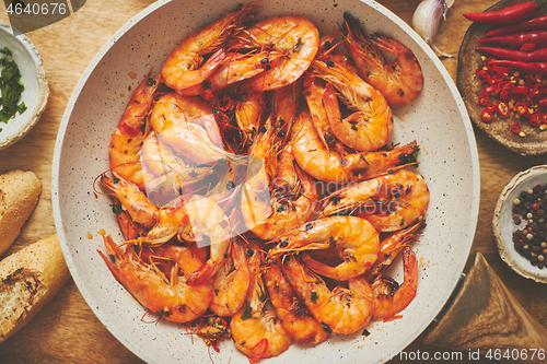 Image of Traditional fried tiger prawn with garlic bread as top view served in a white frying pan