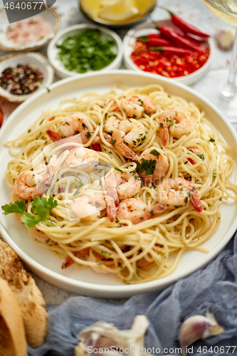 Image of Spaghetti with shrimps on white ceramic plate and served with glass of white wine