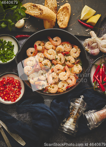 Image of Fried baby Shrimps served on iron pan and fresh herbs and ingredients. Top view, flat lay