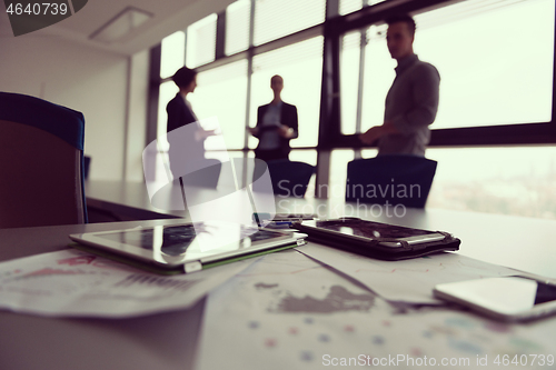 Image of close up of tablet, business people on meeting in background