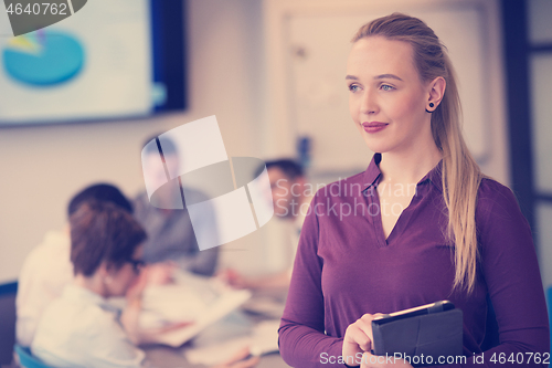 Image of blonde businesswoman working on tablet at office