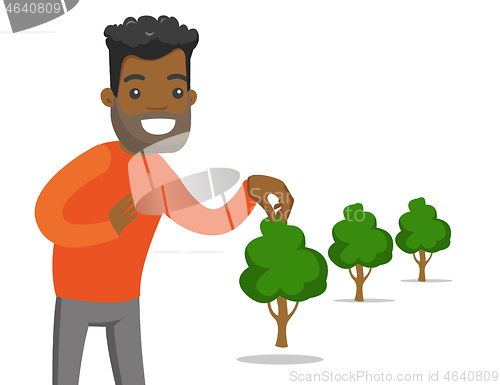 Image of Young african-american gardener plants a tree.