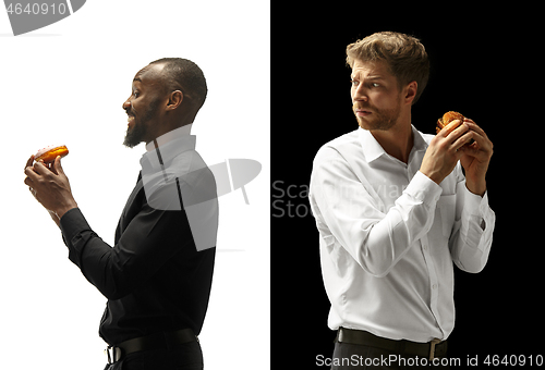 Image of Men eating a hamburger and donut on a black and white background