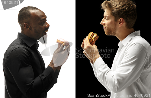 Image of Men eating a hamburger and donut on a black and white background