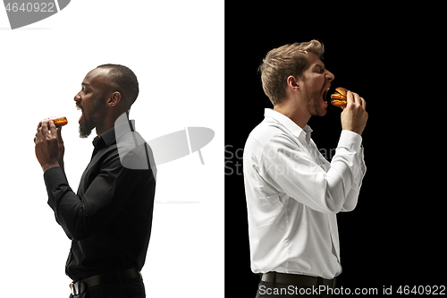 Image of Men eating a hamburger and donut on a black and white background