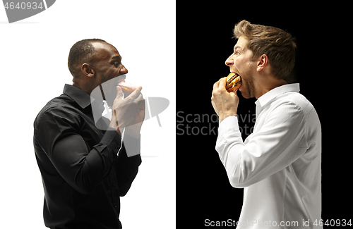 Image of Men eating a hamburger and donut on a black and white background