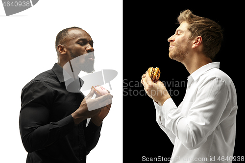 Image of Men eating a hamburger and donut on a black and white background