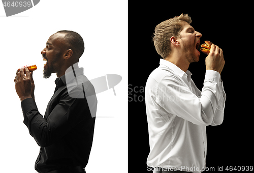 Image of Men eating a hamburger and donut on a black and white background