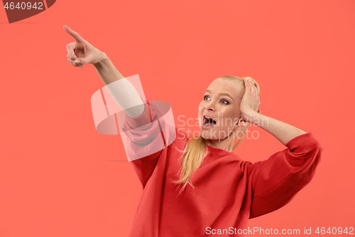 Image of Beautiful woman looking suprised isolated on coral