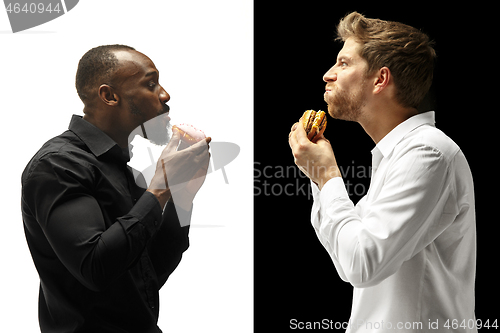 Image of Men eating a hamburger and donut on a black and white background