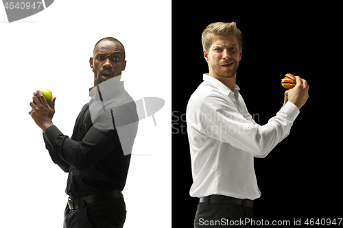 Image of Men eating a hamburger and fruits on a black and white background