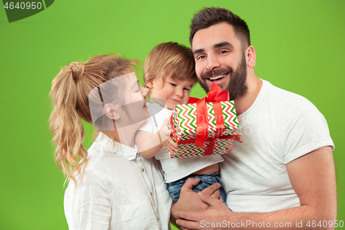 Image of happy family with kid together and smiling at camera isolated on green