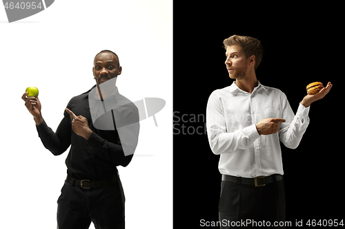 Image of Men eating a hamburger and fruits on a black and white background