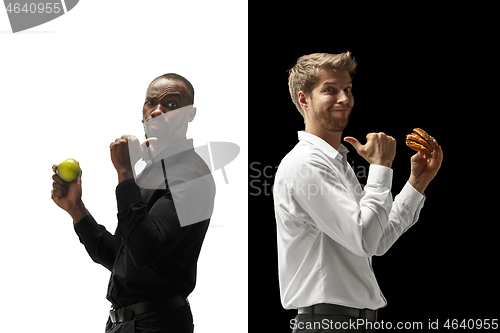 Image of Men eating a hamburger and fruits on a black and white background