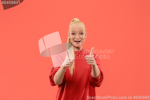 Image of The happy business woman standing and smiling against coral background.