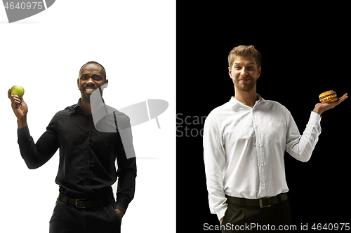 Image of Men eating a hamburger and fruits on a black and white background