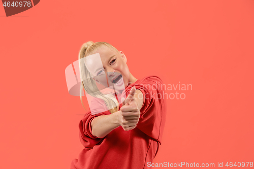 Image of The happy business woman standing and smiling against coral background.