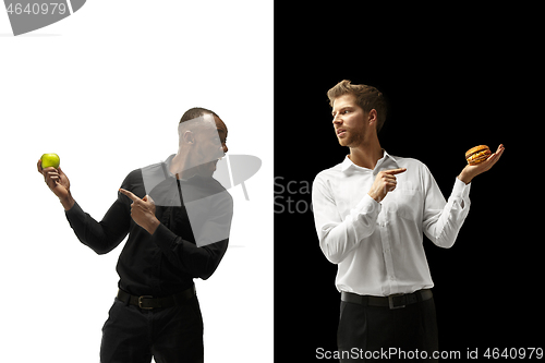 Image of Men eating a hamburger and fruits on a black and white background