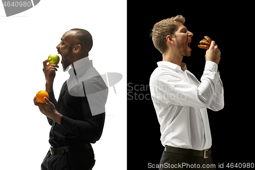 Image of Men eating a hamburger and fruits on a black and white background