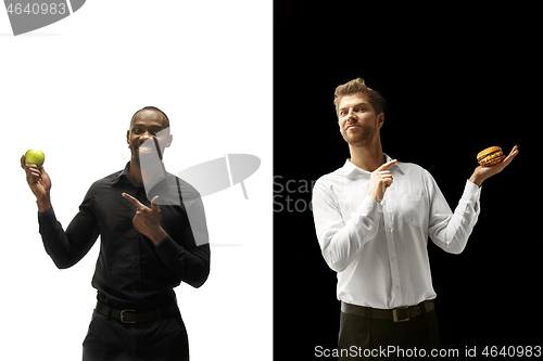 Image of Men eating a hamburger and fruits on a black and white background