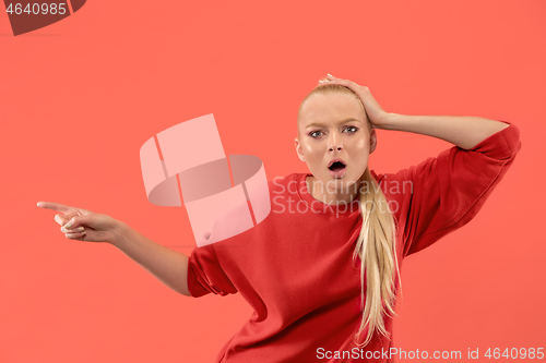 Image of Beautiful woman looking suprised isolated on coral