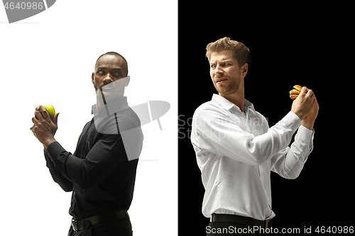 Image of Men eating a hamburger and fruits on a black and white background