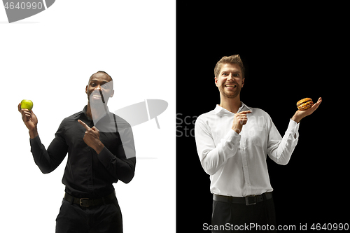 Image of Men eating a hamburger and fruits on a black and white background
