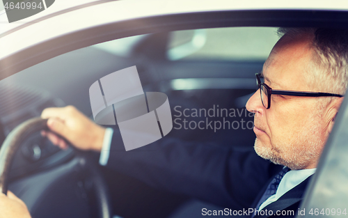 Image of happy senior businessman driving car