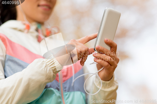 Image of woman listening to music on smartphone outdoors