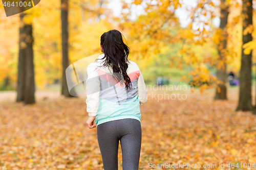 Image of young woman running in autumn park