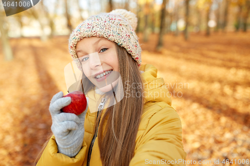 Image of happy girl with apple taking selfie at autumn park