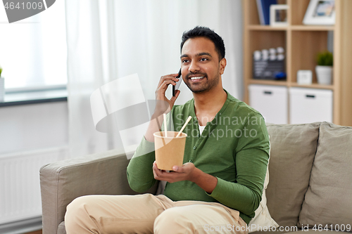 Image of smiling indian man eating takeaway food at home