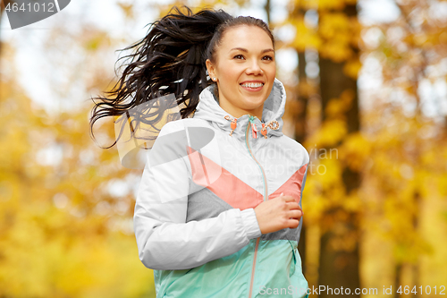 Image of young woman running in autumn park