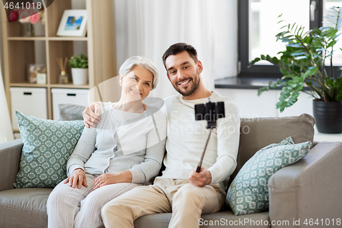 Image of senior mother with adult son taking selfie at home