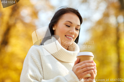 Image of woman drinking takeaway coffee in autumn park