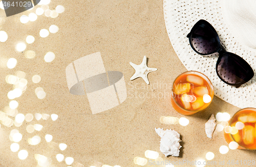 Image of cocktails, sun hat and sunglasses on beach sand