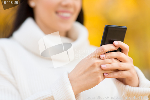 Image of woman using smartphone in autumn park