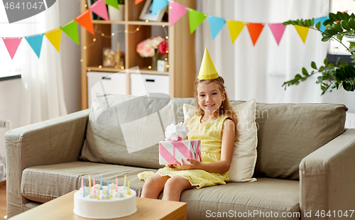 Image of happy girl in party hat with birthday gift at home