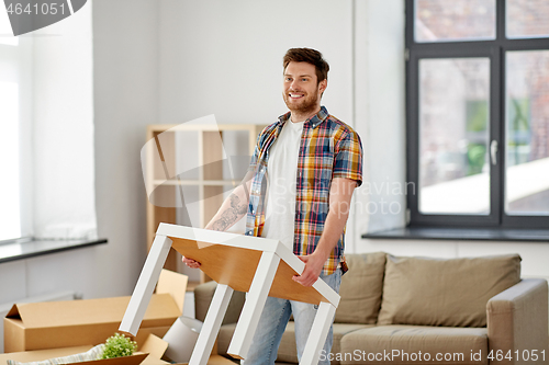 Image of happy man with table moving to new home