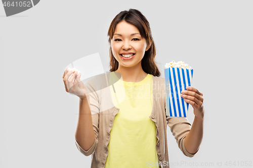 Image of smiling asian woman eating popcorn