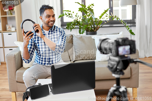 Image of male blogger with headphones videoblogging at home