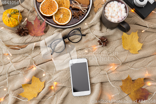 Image of smartphone, hot chocolate and autumn leaves