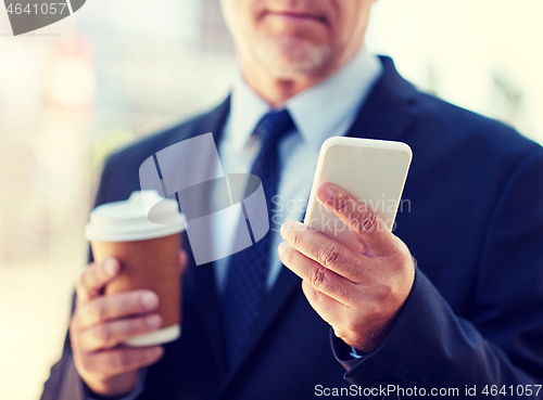 Image of senior businessman with smartphone and coffee