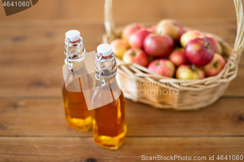 Image of apples in basket and bottles of juice on table