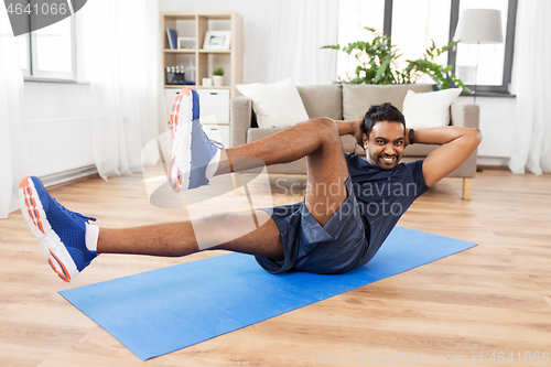 Image of indian man making abdominal exercises at home